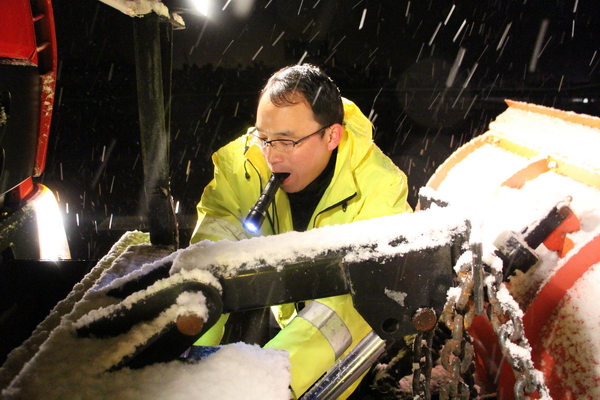 風雪中，馬巢公司夜班除雪隊員李夫勝正在調試除雪鏟大燈.jpg